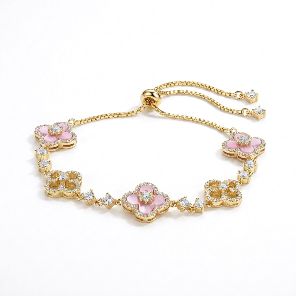 Exquisite gold-toned bolo bracelet featuring alternating pink enamel-effect clover motifs and pavé simulated diamond clovers on a white background.
