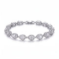 A woman's arm wearing a sparkling rhodium-plated bracelet featuring pear-cut zircon stones, each framed by a pave halo, exuding refined elegance.
