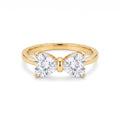 Golden ring with two heart-shaped clear stones forming a delicate bow, centered on a clean white background, showcasing its intricate design and brilliant sparkle.