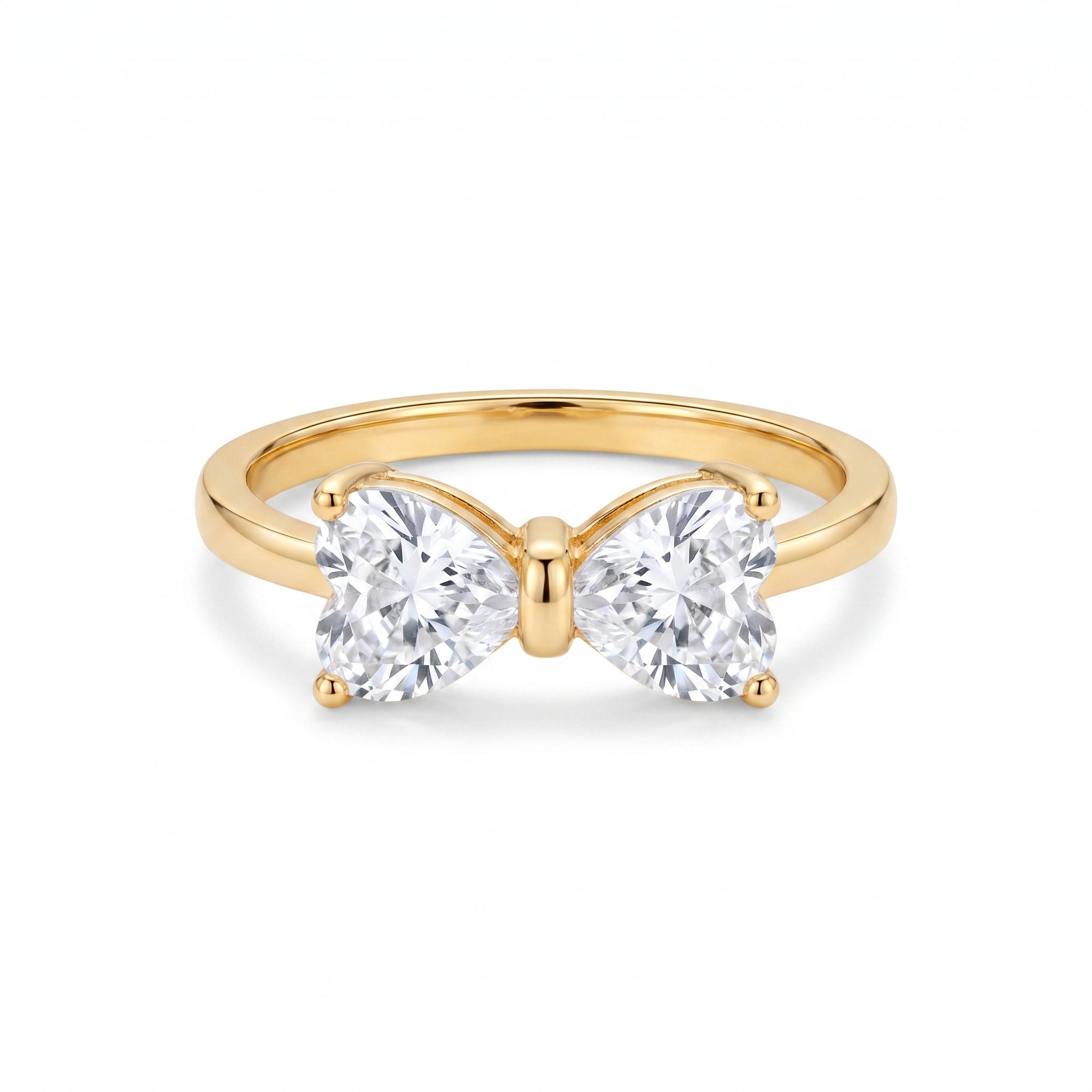 Golden ring with two heart-shaped clear stones forming a delicate bow, centered on a clean white background, showcasing its intricate design and brilliant sparkle.