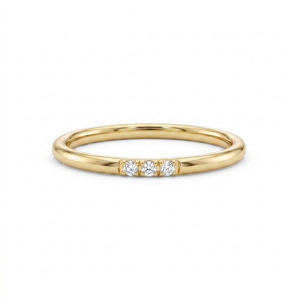 A minimalist 14k yellow gold diamond trio band ring displayed on a pristine white background