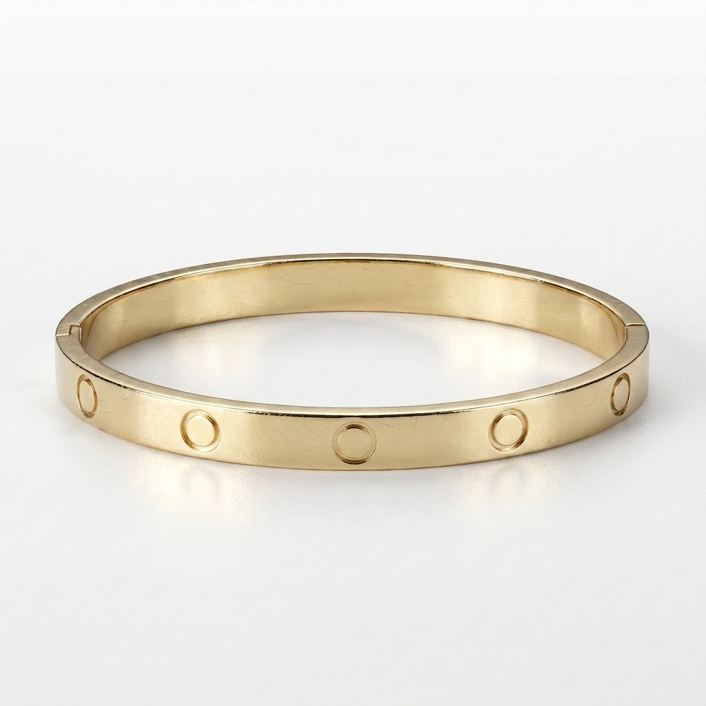 Close-up of a gleaming gold-toned titanium steel bangle with iconic screw motifs and a visible hinge clasp, presented on a pristine white background.