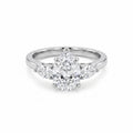 Close-up of a luxurious three-stone ring featuring a pear-cut cubic zirconia center stone flanked by two smaller pear-cut cubic zirconia side stones, set in a gleaming white gold plated band on a pristine white background.
