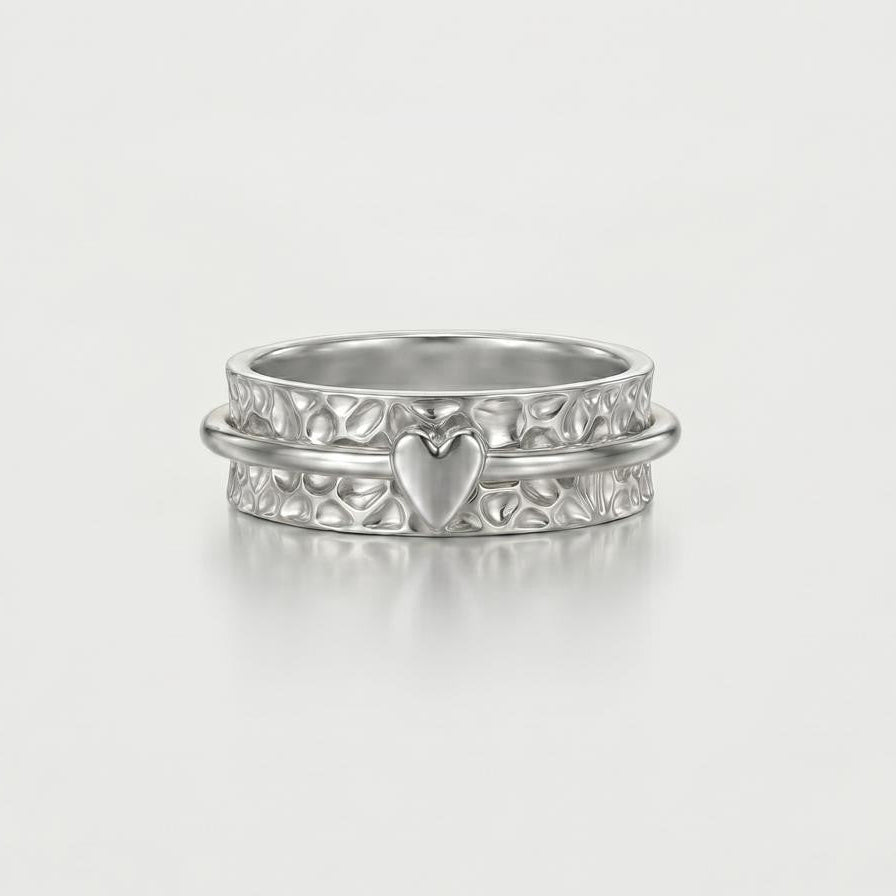 Silver ring with heart design on a light gray background